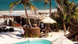 a group of people standing on the beach next to a pool at Tulum Escape - Private Hot Tub, Steps to Free Beach in Tulum