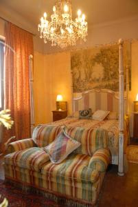 a bedroom with a bed with a couch and a chandelier at Villa Valentino in Canale