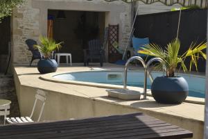 a swimming pool with two potted plants on a patio at Chambre d'hôte avec piscine partagé à disposition in Chef-Boutonne