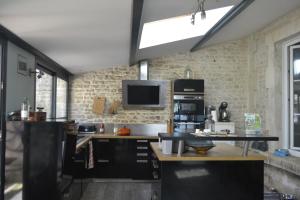 a kitchen with black cabinets and a tv on the wall at Chambre d'hôte avec piscine partagé à disposition in Chef-Boutonne