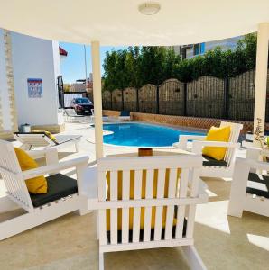 eine Terrasse mit Stühlen und einem Swimmingpool in der Unterkunft Magawish Hurghada Apartement 1 in Hurghada