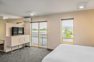 a room with a bed and a tv and windows at Quality Inn Sunshine Suites in Terrace