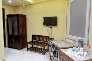 a living room with a bench and a tv on the wall at The Bayan Elegance Hotel in Jaipur