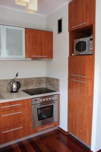cocina con armarios de madera y microondas en Ustka Apartament Na Wydmie en Ustka