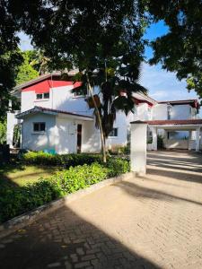 a white house with a palm tree in front of it at BEACH FRONT 3 Bedroom Bungalow in Mombasa