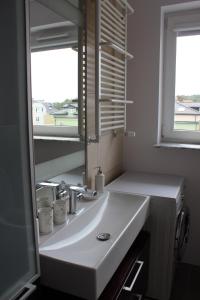 Ustka Apartament Na Wydmie في أوستكا: حمام مع حوض أبيض ومرآة