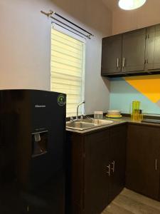 a kitchen with a black refrigerator and a sink at Discreet luxury in an exclusive area in Matamoros