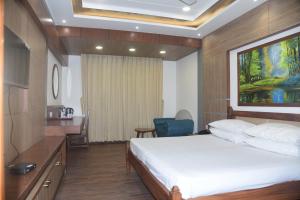 a bedroom with a bed and a desk and a chair at Indo Hokke Hotel in Rājgīr +51 photos