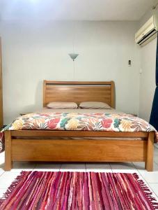a bedroom with a wooden bed with a red rug at Nenuphar 3 Bedroom-Apartment in Flic-en-Flac +12 photos
