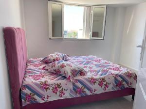 1 cama en un dormitorio con edredón rosa y blanco en Hauvre Marin, en Kelibia