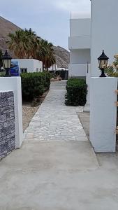 a stone walkway next to a white building with a street light at Perissa Black Rock Lotus in Perissa