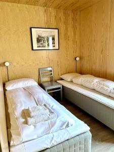a bedroom with two beds and a chair in it at Fjordview Ryten 2 Retreat in Sund