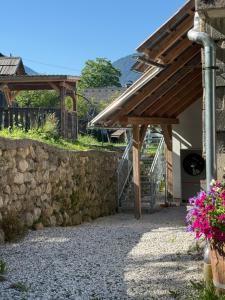 a stone wall next to a building with a wooden roof at Apartma Klemenc in Bohinj