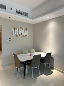 アジュマーンにあるAppartement 1BR de 2024 avec piscine et salle de sportの白いテーブルと椅子のあるダイニングルーム