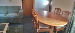 a wooden table and chairs in a living room with a couch at Glenedagh Oughter B&B in Ballycastle