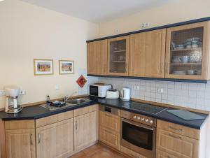 a kitchen with wooden cabinets and black counter tops at Störtebeker 07 in Kühlungsborn +6 photos