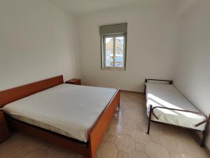 Dos camas en una habitación pequeña con ventana. en Casa Ischia, en Marina di Schiavonea