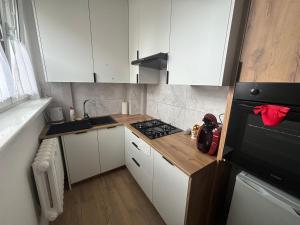 a small kitchen with a stove and white cabinets at Apartament Mazurski Azyl in Szczytno