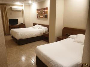 a hotel room with two beds and a television at Hostal Moreno in Silla