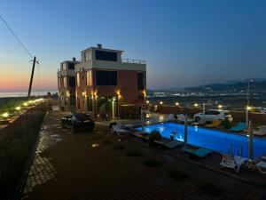 a villa with a swimming pool at night at Laia Hotel House in Itʼkhvisi