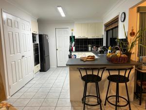 Una cocina con encimera y dos taburetes de bar. en Orchid House Shared, en Stanthorpe