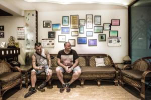 Dos hombres sentados en un sofá en una habitación con cuadros en la pared. en Smyle Inn - Best Value Hotel near New Delhi Station, en Nueva Delhi