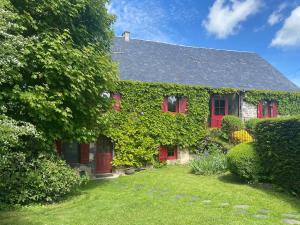 une maison recouverte de lierre avec des portes et des fenêtres rouges dans l'établissement Longère 7 personnes - 4 chambres - 3 SdB Orcival, à Vernines