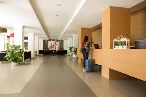 a woman standing in a lobby with a suitcase at Toscana Ambassador in Poggibonsi