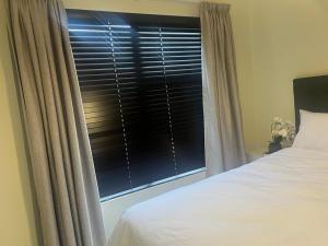Un dormitorio con una cama y una ventana con persianas. en The Nest at Greenstone Gate, en Vosburg