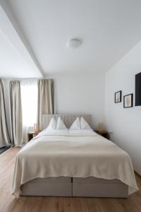 a white bedroom with a large bed with white sheets at FarawayHomes Studio Fohnsdorf #13 in Fohnsdorf