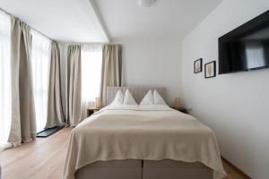 a bedroom with a bed with white sheets and a television at FarawayHomes Studio Fohnsdorf #13 in Fohnsdorf