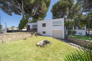 ein weißes Haus in einem Hof mit einer Steinmauer in der Unterkunft Casa Can Picafort in Can Picafort