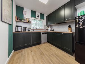 a kitchen with dark green cabinets and a refrigerator at Chatka Czarodzieja in Parlin +27 photos