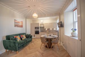 a living room with a green couch and a table at Covesea Lighthouse Cottages in Lossiemouth