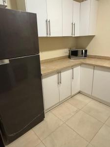 カイロにあるHotel apartments Ninety Avenue New Cairoの白いキャビネットと黒い冷蔵庫のあるキッチン