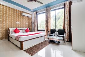 a bedroom with a bed and two chairs and a window at Super Hotel O Legacy Raebareli in Rāe Bareli