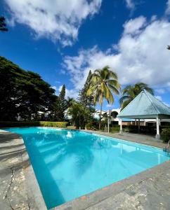 a blue swimming pool with palm trees in the background at Nenuphar 3 Bedroom-Apartment in Flic-en-Flac