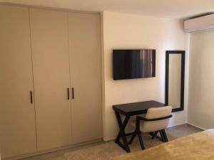 Un dormitorio con un escritorio y un televisor en la pared. en Casa del Sol - Kalathas, en Kalathas