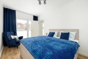 a bedroom with a blue bed and a blue chair at Apartament na Brzozowej in Międzywodzie