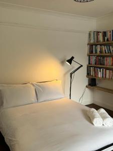 a bedroom with a white bed with a lamp and books at Zarza House 4 bedroom Home Sleeps 8 large Garden wifi and free Parking in Hatfield