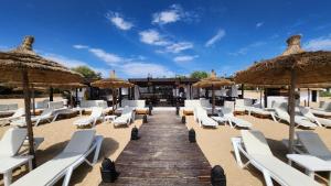 a beach with white lounge chairs and umbrellas at appartement avec vue sur mer avec belle pergola bioclimatique au terrasse in M'diq