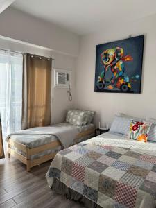 a bedroom with two beds and a painting on the wall at mira's condo unit in Amani Grand Residences near Mactan Int'l Airport in Mactan Cebu International