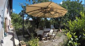 a table and chairs under an umbrella in a yard at Gîtes spacieux avec jardin in Chérisey