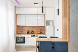 a kitchen with white cabinets and a wooden table with blue chairs at Apartman 51 Sarajevo in Donje Mladice