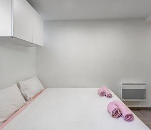 a white room with a bed with pink towels on it at Studio Centre Ville proche TRAM & Port, Wifi Gratuit in Nice