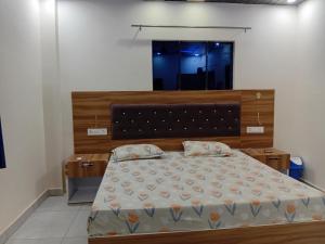 a bedroom with a large bed with a wooden headboard at Corbett view homestay in Belparāo +5 photos