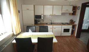 a kitchen with a table and chairs and a kitchen with white cabinets at Ferienwohnung in Gamlitz