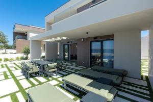 a house with a patio with chairs and tables at Adria Resort SEAFRONT Villa C Private Pool Pet Friendly in Zaton