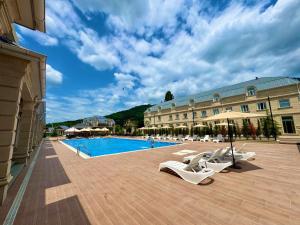 a hotel with a swimming pool with white lounge chairs at Gabala Bless Hotel Cottage in Gabala