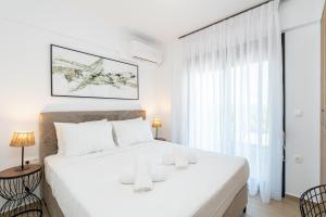a white bedroom with a large bed and a window at White Dream Residential Complex in Skala Rachoniou